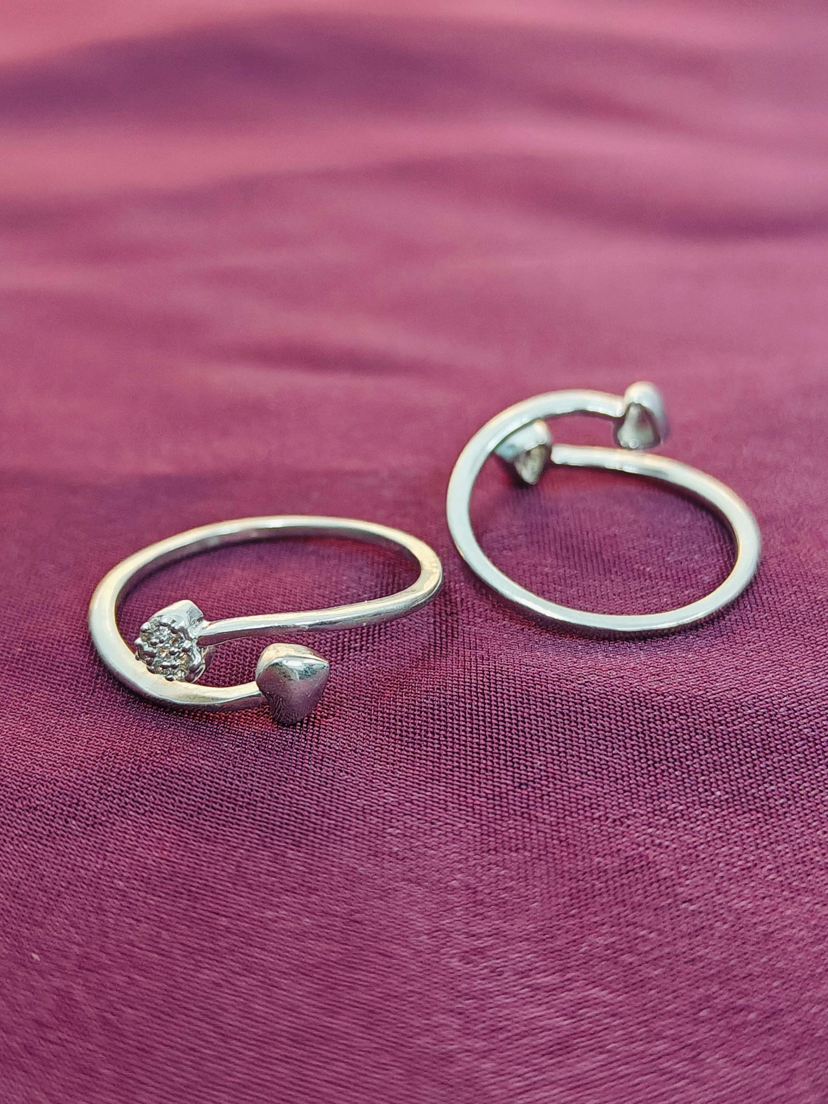 Silver hoop earrings with heart and diamond-shaped charms on a purple fabric background